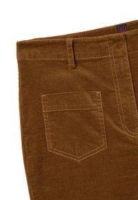 Braune Cordhosen mit Gesäßtasche, gesteppten Nähten und einem Etikett am Bund. Weiche Textur und maßgeschneiderte Designdetails.