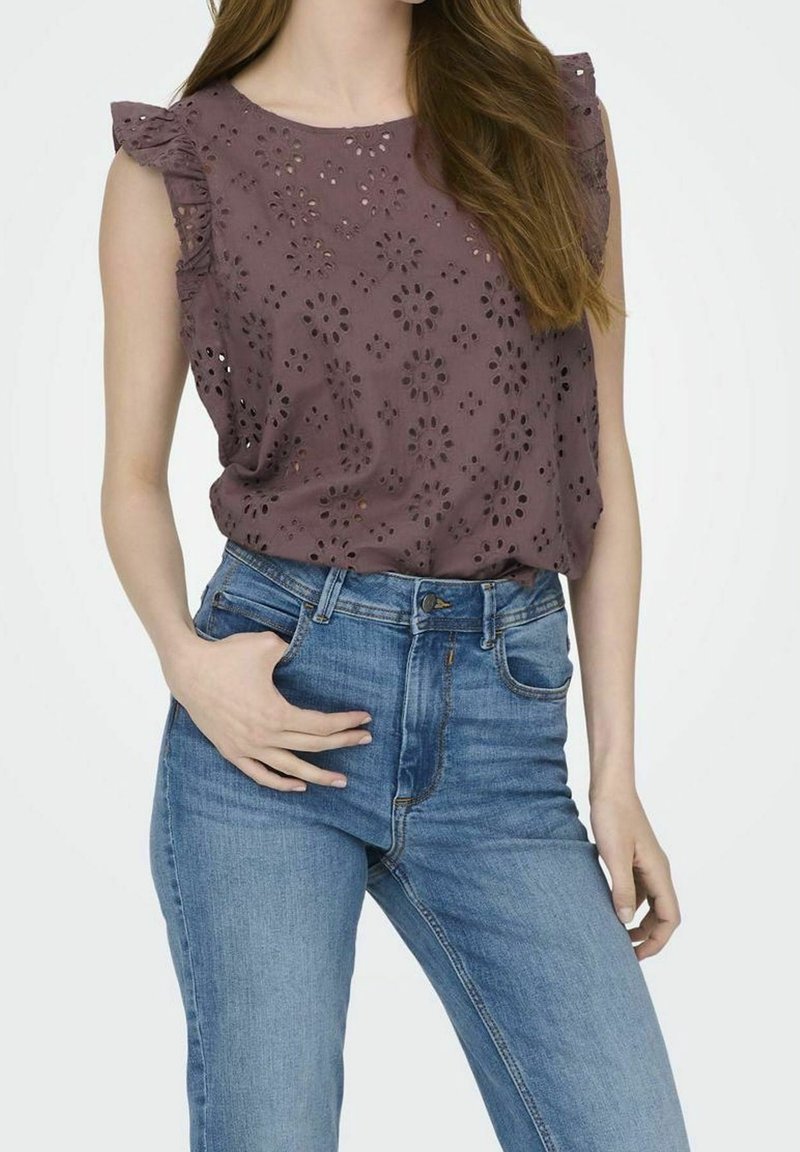 Top viola con ricami floreali e spalle arricciate, abbinato a jeans cerulei a vita alta. Il top presenta un design perforato.