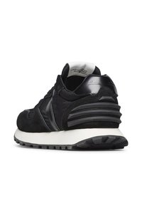 Sneaker nera con pannelli in suede e sintetico, suola intermedia bianca imbottita, suola esterna nera testurizzata e linguetta sul tallone imbottita con design in rilievo.