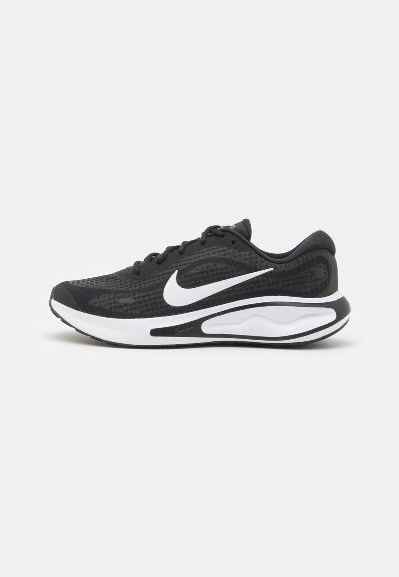 Scarpe da corsa Nike nere e verde scuro con logo swoosh bianco e suola imbottita bianca, mostrate in profilo laterale su uno sfondo semplice.
