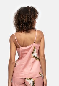 Roze camisole met verstelbare bandjes en een losse pasvorm, versierd met een kraanmotief in wit, zwart en gouden accenten.