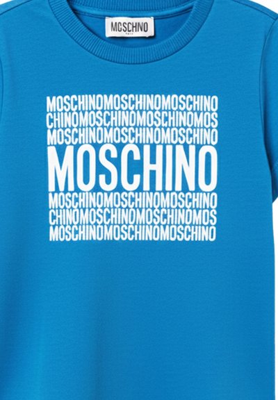 Blå T-shirt med hvidt gentaget "MOSCHINO" tekst, der danner et kvadratisk mønster centreret på brystet, med en større "MOSCHINO" i midten.