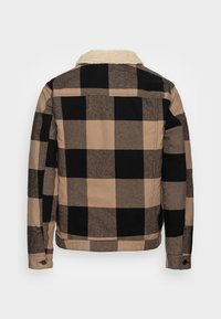 Buffalo-sjekk jakke i svart og beige, med en pelskrage, lange ermer og rett snitt med knappelukking ved ermene.