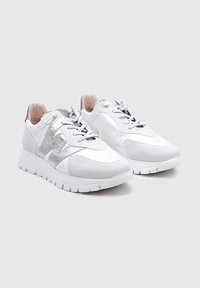Zapatillas deportivas blancas que presentan materiales de cuero y gamuza, un acento plateado texturizado y un cuello acolchado con un diseño de cordones.