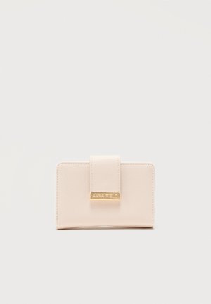 Cartera compacta beige con superficie texturizada y una correa frontal con una placa metálica dorada grabada con "ANNA FIELD".