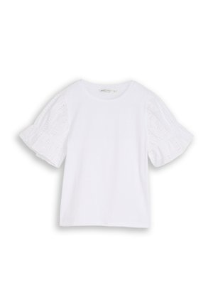Blouse blanche à manches courtes avec encolure ronde et manches bouffantes ornées de dentelle ajourée, présentée sur un fond uni.
