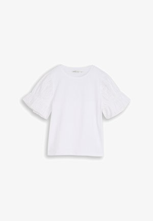 Blouse blanche à manches courtes avec encolure ronde et manches bouffantes ornées de dentelle ajourée, présentée sur un fond uni.