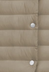 Beige Daunenjacke mit gesteppten Abschnitten, glatter Textur und silbernen Knopfverschlüssen.