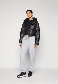 Fekete steppelt dzseki rövidített fazonnal, világosszürke melegítőnadrággal és fekete tornacipővel párosítva. Sima textúra, állítható derékpánt.