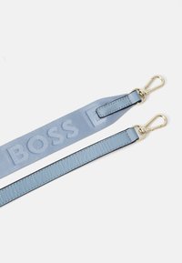 Cinturino in blu chiaro realizzato in pelle e tessuto presenta il logo "BOSS" in rilievo. Clip in metallo dorato alle estremità, texture liscia e finitura elegante.