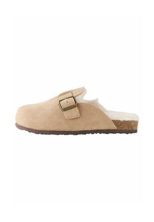 Beige mokkasiinit, joissa on pyöristetty kärki, säädettävä solki ja tekoturkisvuori. Korkkipohja ja kumipohja tarjoavat mukavuutta.