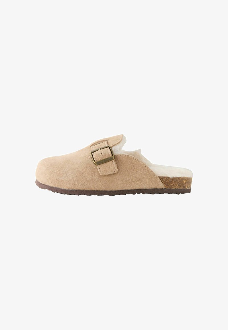 Zoccolo beige in pelle scamosciata slip-on con cinturino regolabile con fibbia, fodera interna soffice e suola in sughero con fondo in gomma rigato.
