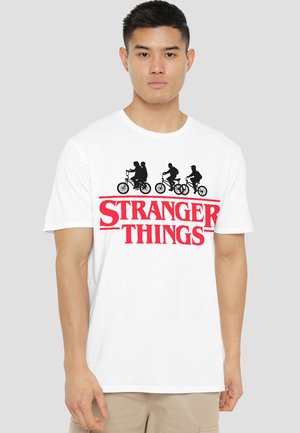 Weißes T-Shirt mit einem schwarzen Silhouetten-Design von drei Personen auf Fahrrädern über dem roten Text "STRANGER THINGS." Kurze Ärmel, Rundhalsausschnitt.