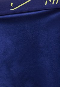 Κοντινή λήψη σκοτεινού μπλε υφάσματος με μερικό κίτρινο κείμενο κεντημένο στην πάνω άκρη.