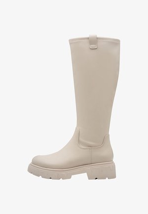 Botte beige jusqu'au genou en matériau synthétique lisse, avec une semelle épaisse et des accents en zigzag. Anse latérale pour un enfilage facile.