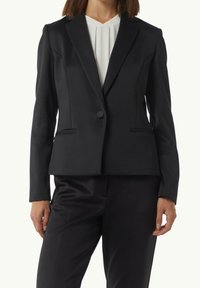 Blazer noir à coupe ajustée, avec revers encochés et fermeture à un seul bouton. Tissu lisse avec poches latérales et coutures discrètes.