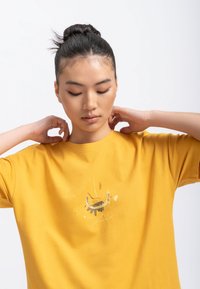 Geel katoenen T-shirt, losse pasvorm, ronde halslijn, met een grafische print in aardetinten, korte mouwen en een zachte textuur.