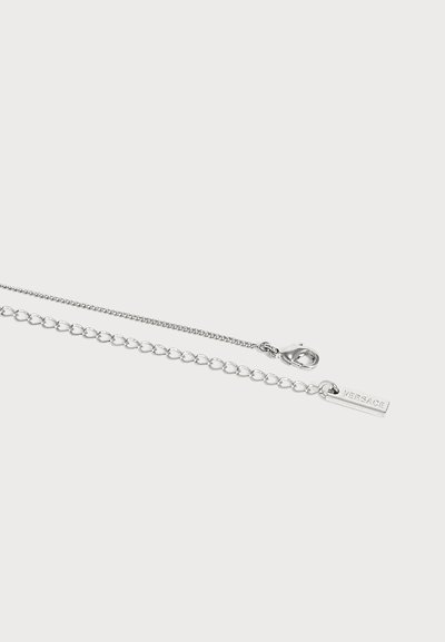 Collier chaîne en argent avec fermoir mousqueton et maillons réglables, doté d'une petite plaque rectangulaire gravée du texte "VERSACE".