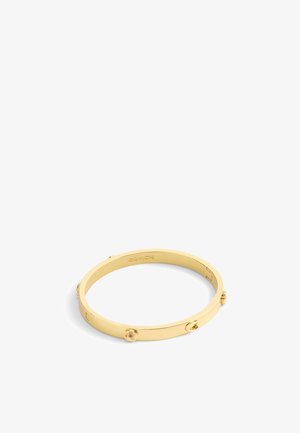 Kultainen metallinen rannekoru, jossa on kukkaakuviot ja sileä, kiiltävä pinta. Selkeä brändin kaiverrus sisäpuolella.