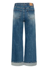 Jean en denim bleu à jambes larges avec revers roulés, deux poches arrière, passants de ceinture, et un patch de marque en cuir marron clair sur la ceinture.