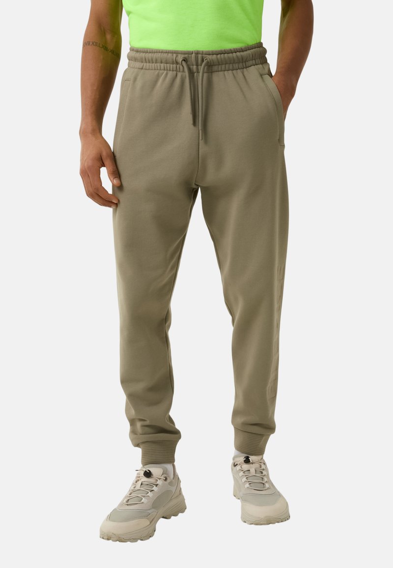 Heren olijfgroene sweatpants gemaakt van zacht materiaal, met een elastische tailleband, zijzakken en taps toelopende boorden.