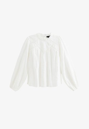 Biała bluzka z długim rękawem i wysokim kołnierzem, wykonana z fakturowanej tkaniny, ozdobiona haftem oraz marszczonymi bufkami na rękawach. Zapięcie na guziki z tyłu.