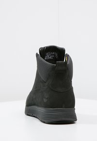 Botas de tobillo de ante negro con acentos texturizados en negro, puntera redonda y suela de goma. Presenta un discreto detalle del logo en el talón.