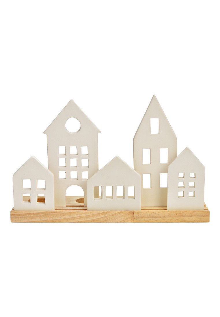Figurine di case in ceramica bianca di altezze variabili con finestre intagliate, posizionate su una base di legno. Forme geometriche semplici e linee pulite.