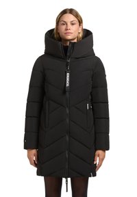 Zwarte pufferjas met een hoge kraag, chevronsteek, ritssluiting en voorklinkers. Heeft een merklabel aan de ritstrekker.