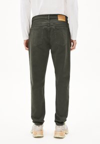 Groene denim broek met een slim fit, voorzien van achterzakken, een leren label en afgewerkt met textiel. Gemaakt met lichte sneakers.