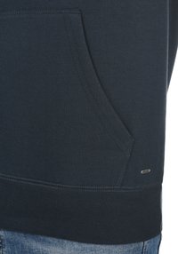Navyblaues Sweatshirt mit Kängurutasche, geripptem Saum und dezentem Metallic-Logo. Glattes Material mit dehnbarem Textil.
