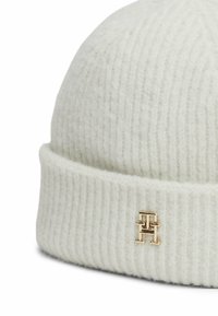 Beanie a coste bianche realizzato in materiale morbido, con un accento di logo dorato sul bordo piegato. Texture liscia con una leggera lucentezza.