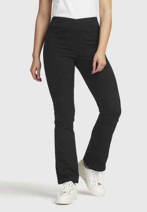 Sorte strækbukser med en glat tekstur, mellemhøj talje og bukser med flare-design, parret med hvide sneakers.