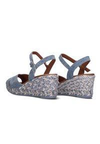 Blue denim wedge sandals with crisscross straps and an open toe. Braided esparto sole adds texture with a woven pattern.