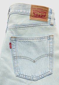 Ανοιχτό μπλε τζιν παντελόνι με ραμμένη πίσω τσέπη, λεπτομέρειες με χρυσή κλωστή και καφέ δερμάτινο ταμπελάκι με λογότυπο στη μέση.