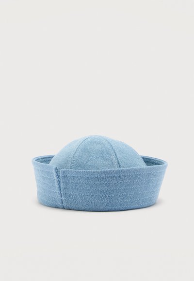 Ανοιχτό μπλε καπέλο ναυτικού από τζιν με στρογγυλή, επίπεδη κορυφή και φαρδύ, διπλωμένο γείσο σε απλό φόντο.