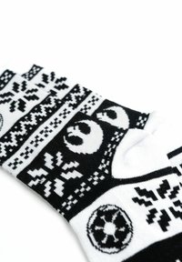 Calzini in bianco e nero con un motivo lavorato a maglia, caratterizzati da disegni geometrici e simbolici, tra cui una stella e motivi floreali.