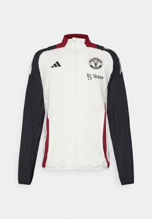 Chaqueta deportiva blanca con mangas negras y detalles rojos. Presenta un cuello, cremallera completa y el logo del Manchester United en el pecho.