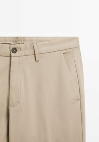 Beige cotton trousers with a smooth texture, featuring a button closure, belt loops, and side pockets. Simple design and tailored fit.