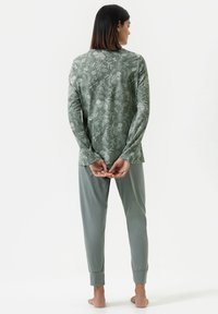 Long-sleeve, patterned top in muted green with floral design; paired with matching, tapered pants in solid green fabric. Soft texture.