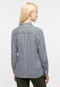 Camicia a righe blu scuro e bianca, maniche lunghe, polsini con bottone e colletto con dettagli a yoke sulla parte posteriore. Tessuto con una consistenza liscia.