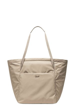 Sac fourre-tout en tissu doux beige avec de longues poignées et une poche extérieure avant, avec un petit détail de logo métallique.