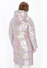 Hosszú, puffos kabát irizáló anyagból, kapucnival. Vízszintes steppelt részekkel és közepes hosszúságú fazonnal rendelkezik, különböző színeket tükröz.