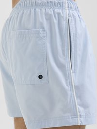 Lichtblauwe zwembroek met een elastische tailleband, zijzak en contrasterende witte rits. Gemaakt van gladde, snel drogende stof.