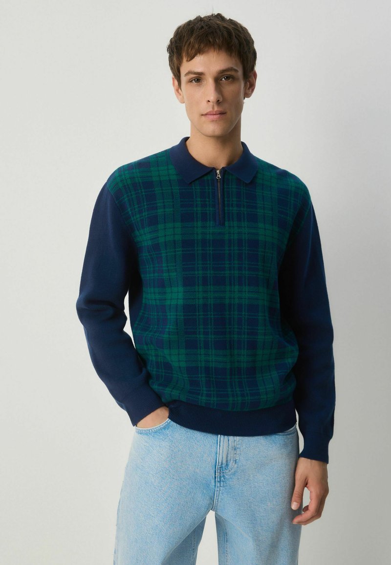 Pullover in Marineblau und grünem Karomuster mit Reißverschlusskragen. Der Strickstoff weist ein strukturiertes Muster auf, hat lange Ärmel sowie gerippte Bündchen und Saum.