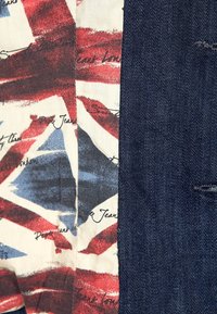 Collage aus Stoff mit einem Union Jack-Design in Rot, Weiß und Blau neben dunklem Denim; zeigt kontrastierende Texturen und Muster.