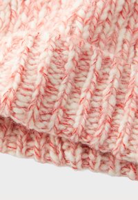 Primer plano de hilo suave y grueso en tonos rosa y blanco, tejido en un patrón de canalé vertical con fibras texturizadas y esponjosas.