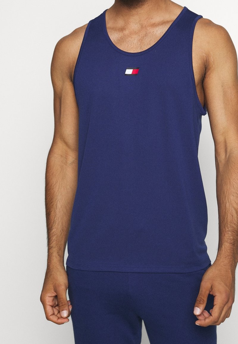 Canotta senza maniche blu navy realizzata in tessuto morbido, con un piccolo logo in rosso, bianco e nero sul petto. Design aderente.