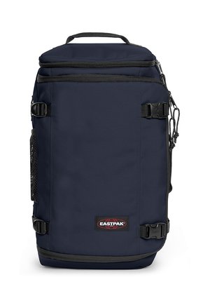 Mochila Eastpak de color azul marino con asa superior, correas ajustables, cierre de cremallera y bolsillo lateral de malla con un parche de logo en la parte frontal.