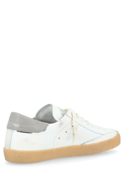 Sneaker bianca in pelle con accento grigio sul tallone, lacci crema e suola in gomma testurizzata color caramello. Presenta un design semplice e linee pulite.